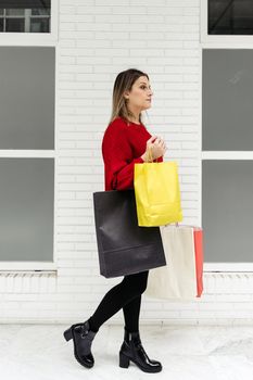 Adult woman walking through a mall with colorful shopping bags.