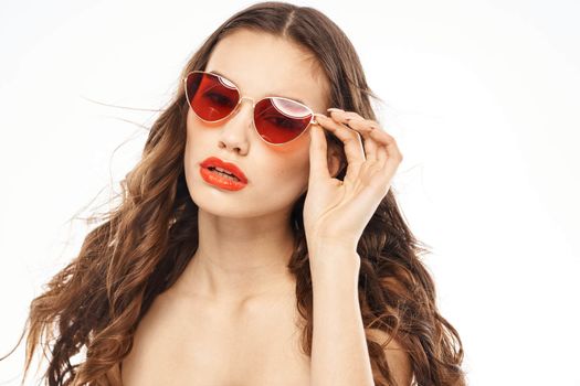 Portrait of brunette woman in sunglasses naked shoulders light background. High quality photo