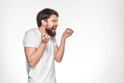 Bearded man in white t-shirt gesture with hands emotions light background. High quality photo