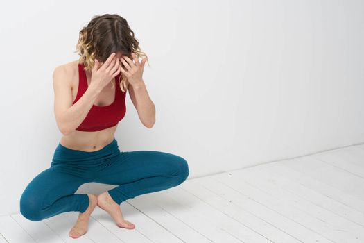 woman doing yoga full length indoors blue leggings red tank top. High quality photo