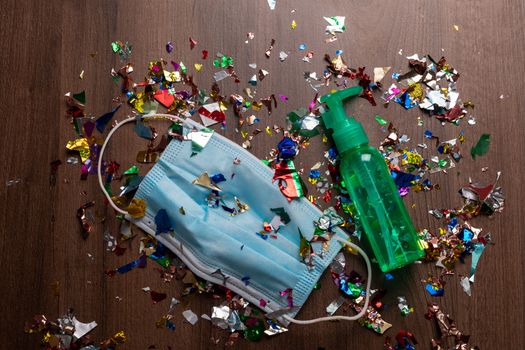 Facemask and sanitizer bottle droped on flor with confetti after celebration new year 2021 party background stock image