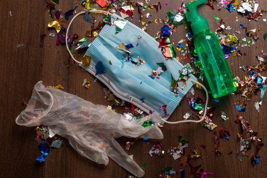 Facemask and sanitizer bottle droped on flor with confetti after celebration new year 2021 party background stock image