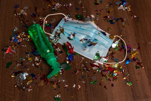 Facemask and sanitizer bottle droped on flor with confetti after celebration new year 2021 party background stock image