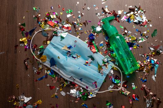 Facemask and sanitizer bottle droped on flor with confetti after celebration new year 2021 party background stock image