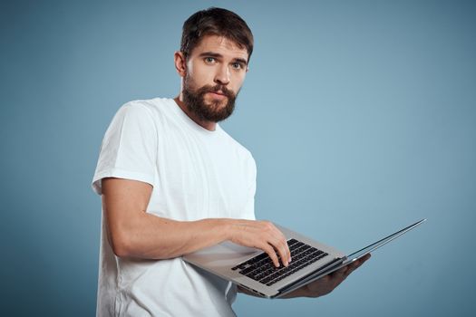 Emotional man with laptop in hands on blue background monitor keyboard internet model cropped view. High quality photo