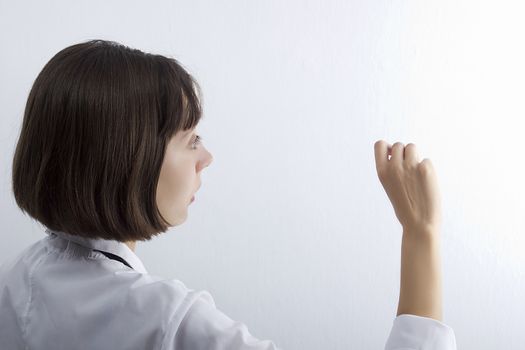Female medical student with chalk in hand on white background