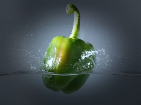 Vintage green bell peppers thrown into the water with a splash of water.