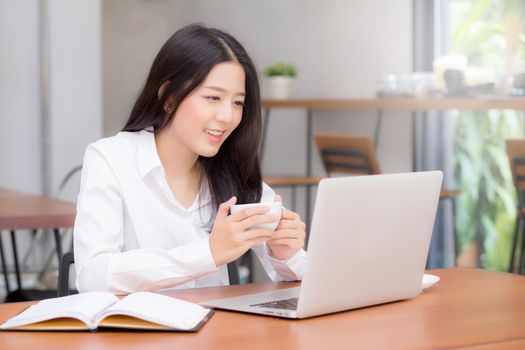 Beautiful asian young woman working online on laptop sitting at coffee shop, professional female freelancer using notebook computer with connect to internet for distance job.