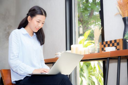 Beautiful asian young woman working online on laptop sitting at coffee shop, professional female freelancer using notebook computer with connect to internet for distance job.