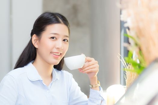 Beautiful  young asian woman drinking coffee and smile in the morning at cafe, girl sitting in coffee shop for breakfast and leisure during free time.