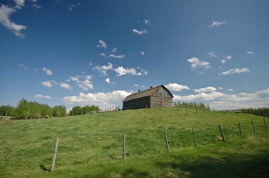 barn on a green hill and blue sky