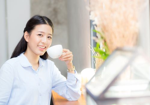 Beautiful  young asian woman drinking coffee and smile in the morning at cafe, girl sitting in coffee shop for breakfast and leisure during free time.