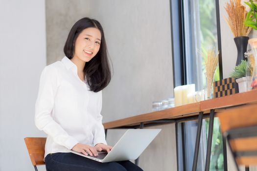 Beautiful asian young woman working online on laptop sitting at coffee shop, professional female freelancer using notebook computer with connect to internet for distance job.