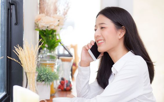 Beautiful young asian woman talking phone and smile in the coffee shop, businesswoman sitting in cafe free time, freelancer female calling telephone, communication concept.