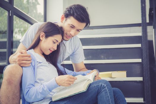 Couple asian handsome man and beautiful woman reading book and smile at home, boyfriend and girlfriend with activities together for leisure, education concept.