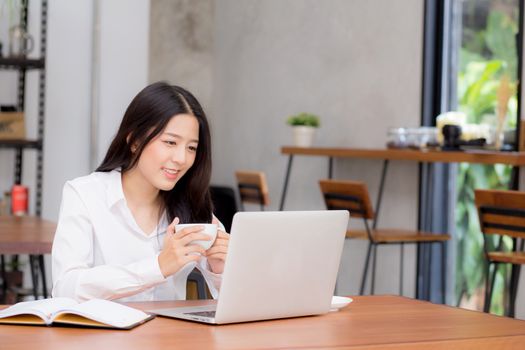 Beautiful asian young woman working online on laptop sitting at coffee shop, professional female freelancer using notebook computer with connect to internet for distance job.
