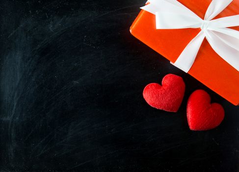 Gift box white bow ribbon and red heart on chalkboard table background top view, february of valentines day in concept.