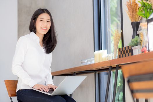 Beautiful asian young woman working online on laptop sitting at coffee shop, professional female freelancer using notebook computer with connect to internet for distance job.