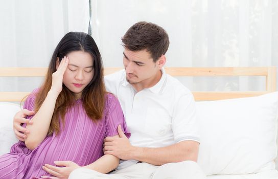 Pregnant asian woman belly acheand feel sick and husband with take care on bedroom, family relationship concept.