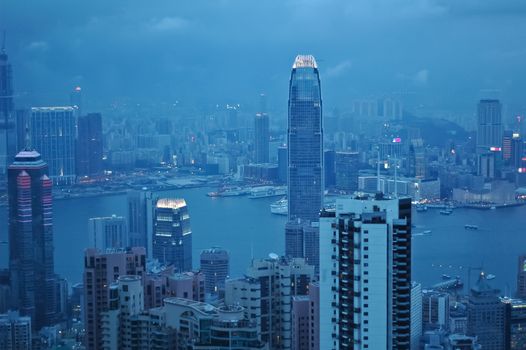 Hong Kong city scene at night with man tall high office buildings and beautiful Victoria bay