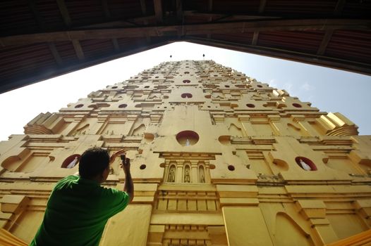 A man shooting photo for golden roof of Sangkhlaburi temple in Western Thailand