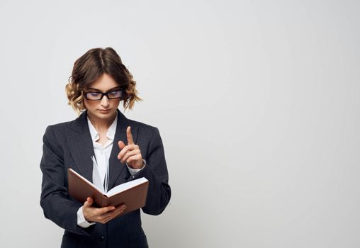 Business woman with a book in her hands on a light background classic suit fashionable hairstyle Copy Space. High quality photo