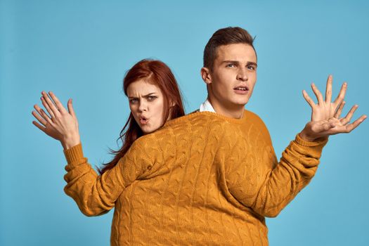 couple in yellow sweater posing against blue background cropped view. High quality photo