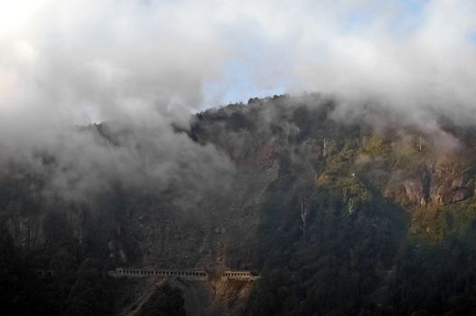 Steep tunnel on the peak of misty mountain in the evening