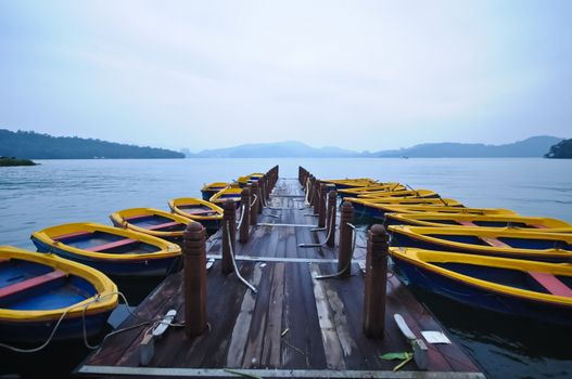 Row boats and wooden jetty in the morning at peaceful lake