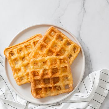 Perfect savory keto waffles. Two ingredients chaffles on plate over white marble background. Eggs and parmesan cheese low carb waffles. Top view or flat lay. Copy space for text or design.