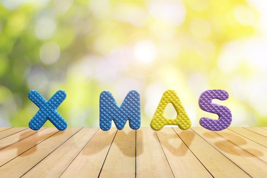 The letters of XMAS are made of plastic on a wooden table, used for Christmas decorations.