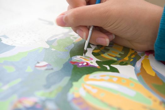 3 - Selective focus on brush tip, painting by numbers. A common Covid lock down quarantine hobby. Close up image with detail and vivid color.