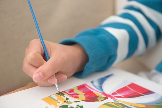 5 - Copy space over blurred stripy jumper background. Bright blues against white. Selective focus on the paint brush as it paints by number