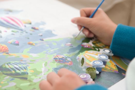 10 - Artist at work painting by numbers. Numbered pots of paint shown using selective focus. Medium perspective on the canvas. Hot air balloon theme