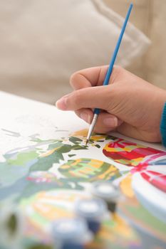 12 - Vertical image of bright blue paintbrush being used for painting. Elegant thin brush painting in green as painting by numbers activity or hobby