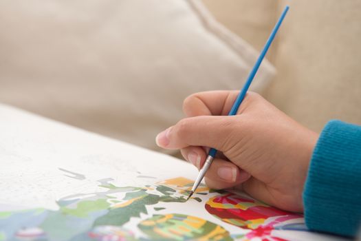 13 - Plenty of copy space in this painting by numbers activity photo. Gentle young hand uses vivid paintbrush and colors to create the artwork