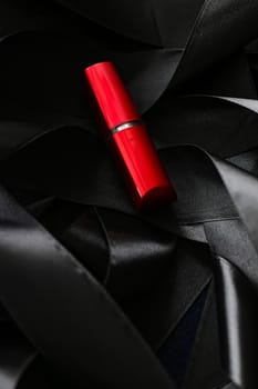 Red lipstick on black silk background, luxury make-up and beauty cosmetics