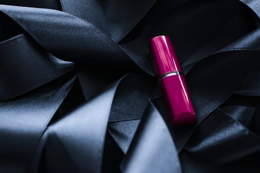 Purple lipstick on black silk background, luxury make-up and beauty cosmetics