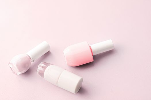 Nail polish bottles on blush pink background, beauty branding