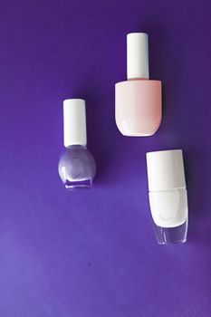 Nail polish bottles on dark purple background, beauty branding