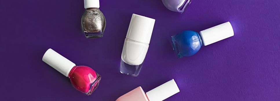 Nail polish bottles on dark purple background, beauty branding