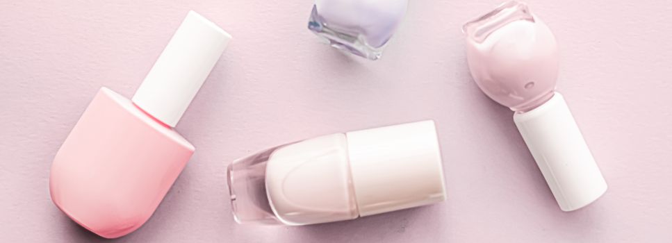 Nail polish bottles on blush pink background, beauty branding