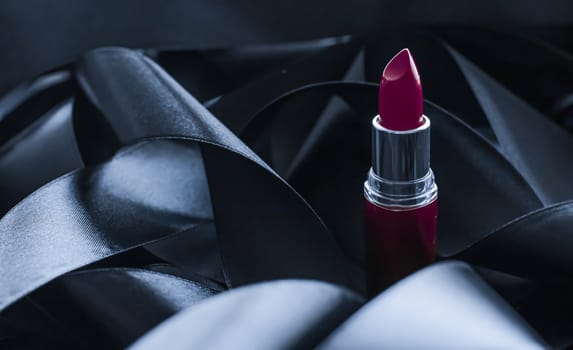 Purple lipstick on black silk background, luxury make-up and beauty cosmetics