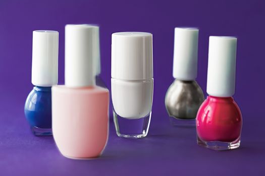 Nail polish bottles on dark purple background, beauty branding