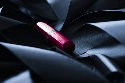 Purple lipstick on black silk background, luxury make-up and beauty cosmetics