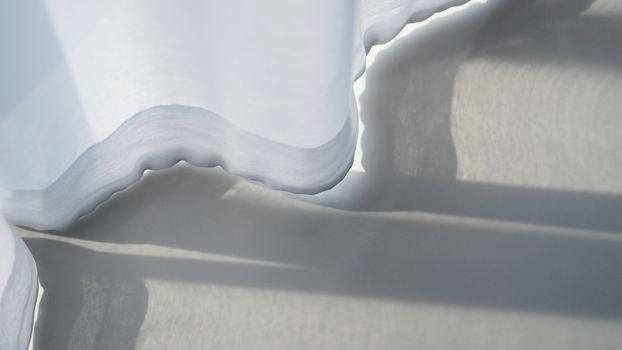 White color transparent airy curtain swaying by wind blow and white floor tile.