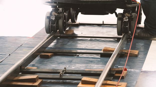 Behind the scenes of production team setting dolly track for video camera equipment before movie shooting in a big studio. 