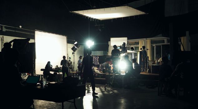 Making of movie video in big production studio and film crew team shooting or recording by professional digital camera and lighting set equipment.