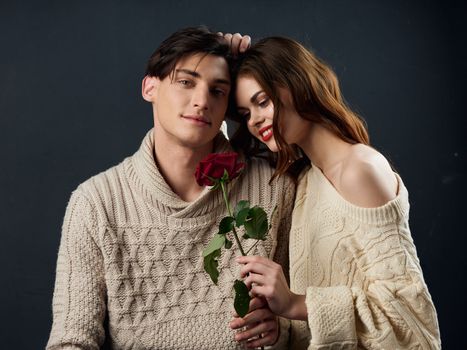 Young couple of lovers rose in hands hugs romance portrait dark background
