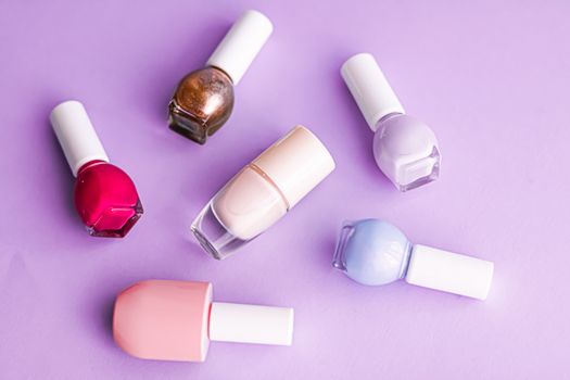 Nail polish bottles on purple background, beauty branding